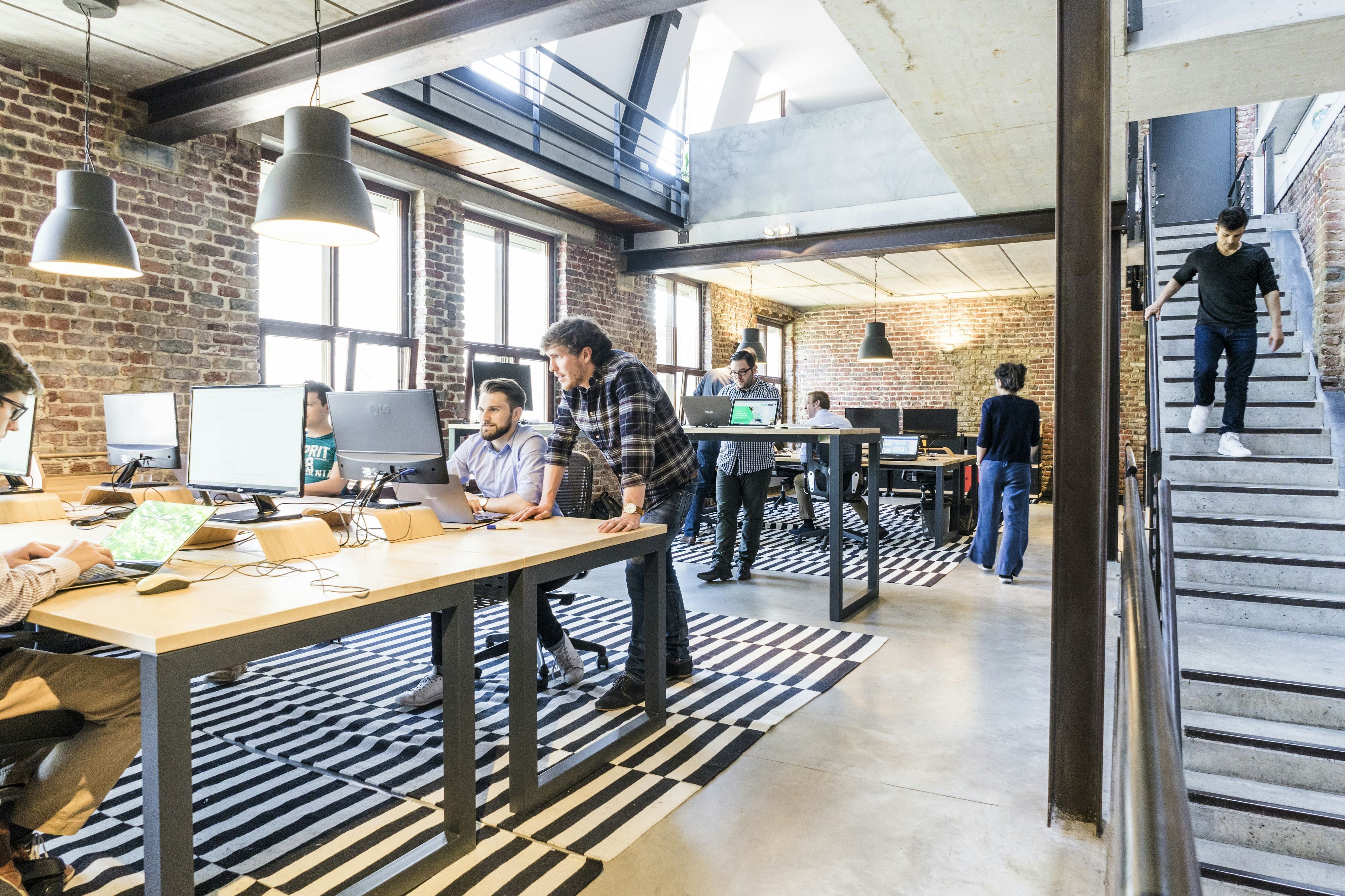 In an open-plan office set in a former workshop, a team at work, at their screens or on the move.