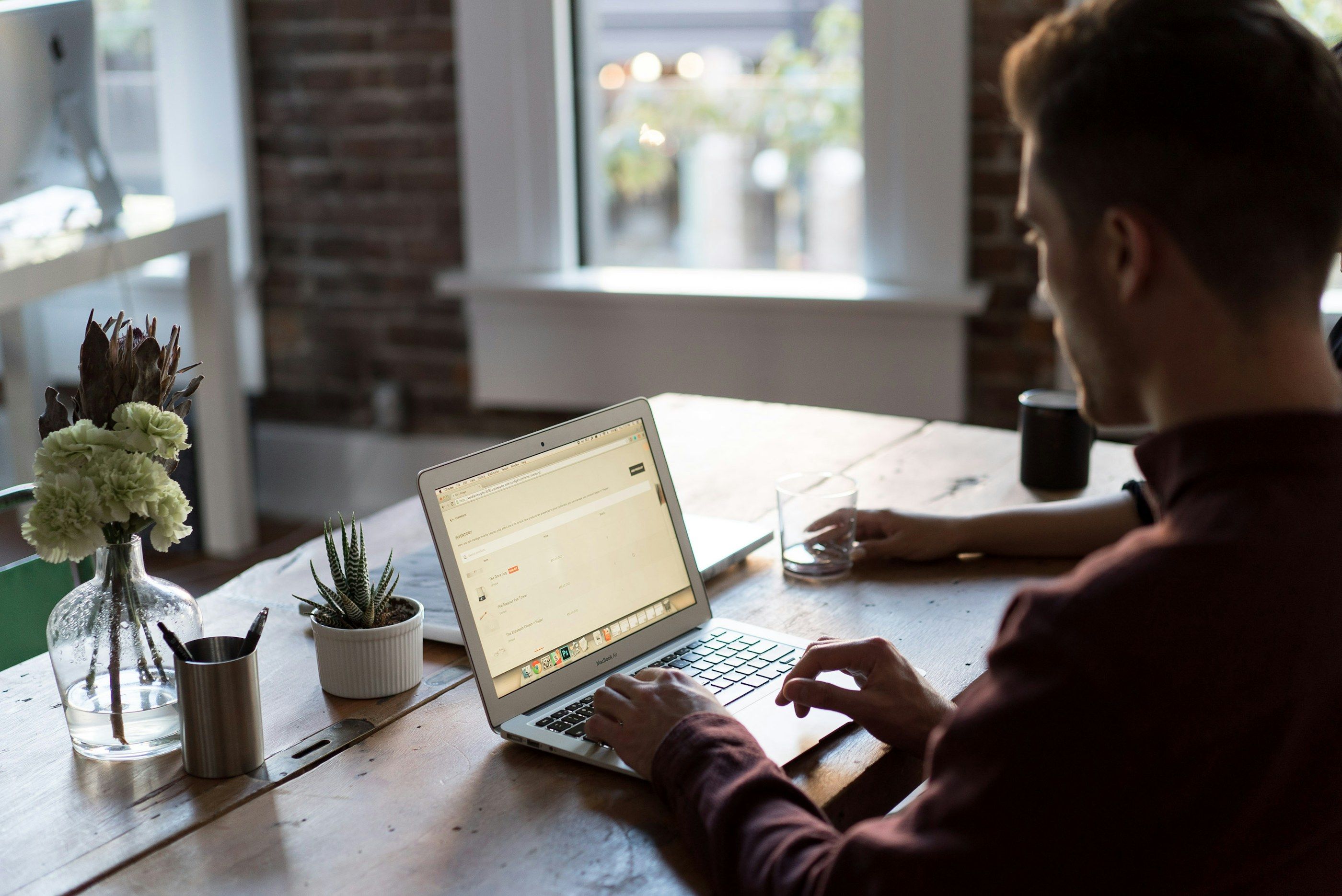 Alone at his desk by a window, an employee answers on his laptop.