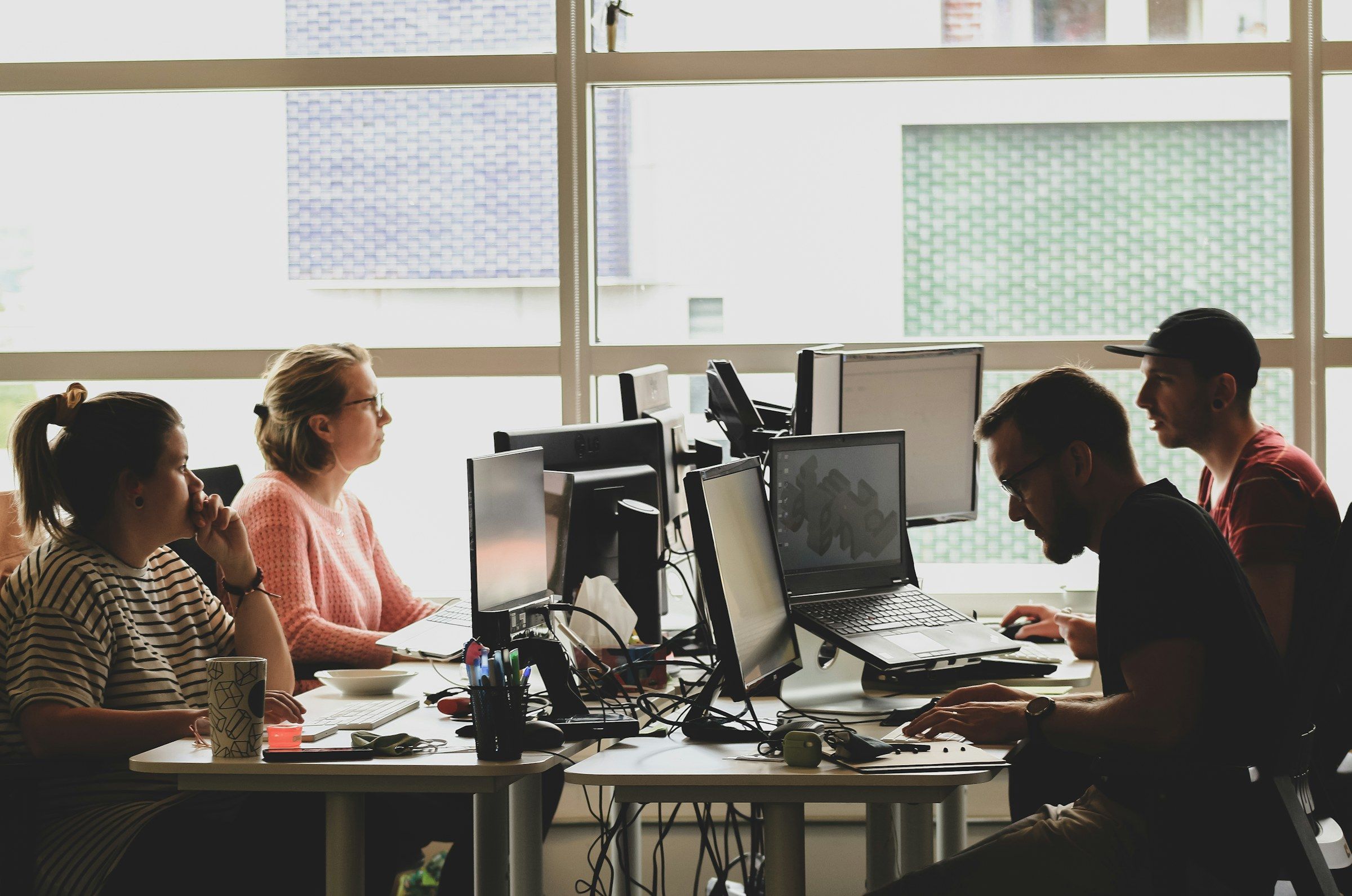 Colleagues work at their computers in a sunlit office.