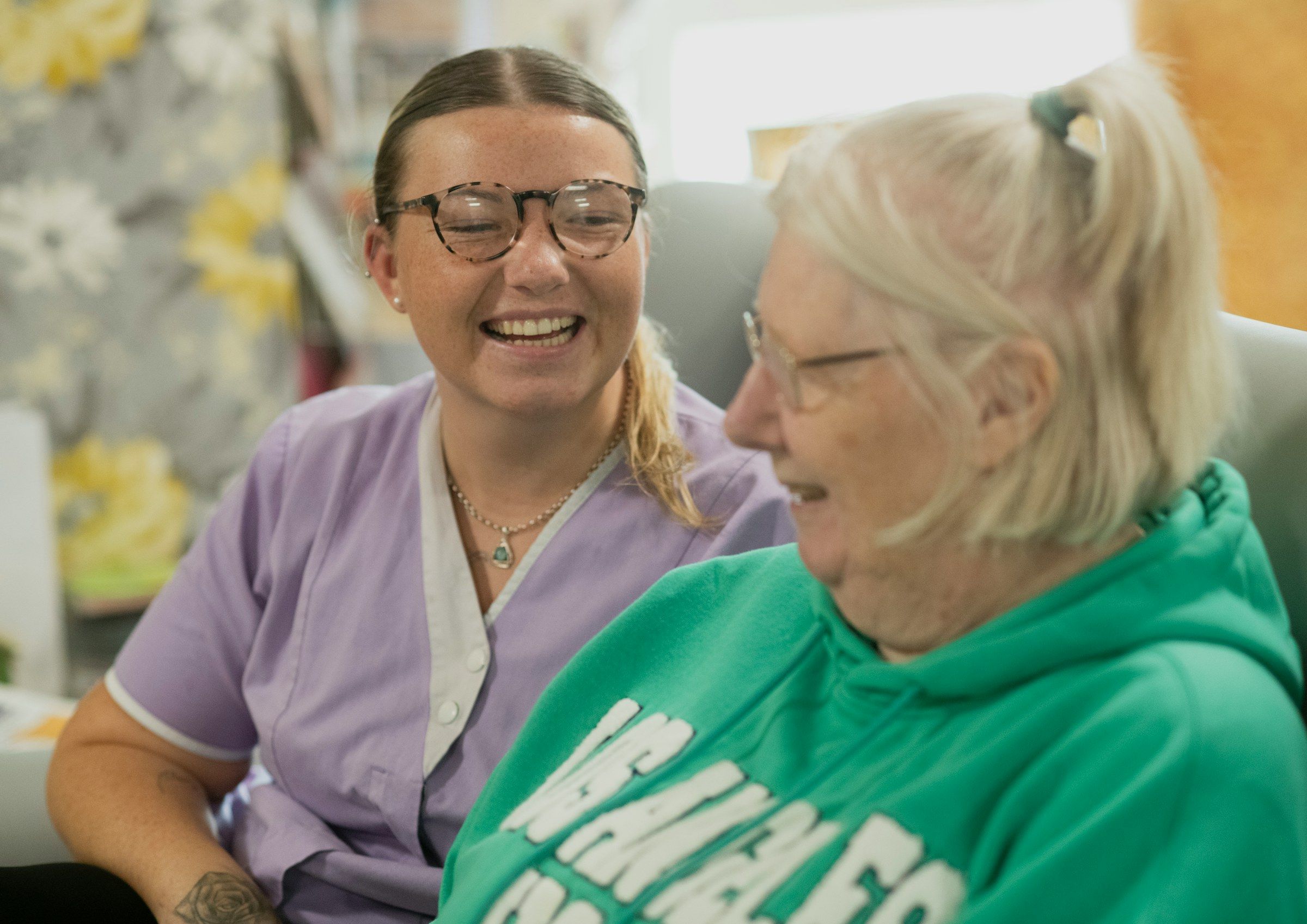 A care worker laughs with an elderly resident.